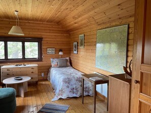 A cozy cabin room with a wooden ceiling, a bed with floral bedding, a desk, a chair, and a map on the wall. - 7 Person Holiday Home in Bjornlunda (Björnlunda)