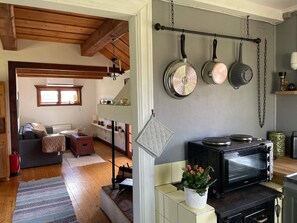 A cozy kitchen with a stove, microwave, and hanging pots. - 7 Person Holiday Home in Bjornlunda (Björnlunda)