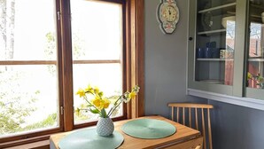 A dining area with a wooden table, two green placemats, a pineapple vase with yellow flowers, and a wall clock. - 7 Person Holiday Home in Bjornlunda (Björnlunda)