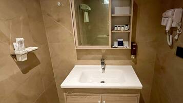 A bathroom with a white sink, a mirror above it, and a shelf with toiletries.