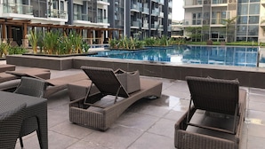 A modern apartment building with a swimming pool, outdoor seating, and lush landscaping. - Cozy 1-bedroom condo with AC, WiFi in adorable Pasay City accross NAIA 3 RW (Pasay City)