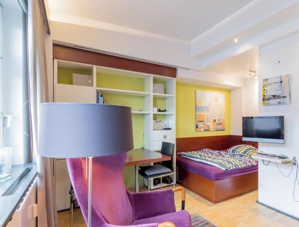 Een moderne hotelkamer met een bed, een bureau, een stoel en een televisie.