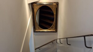 Un escalier doté d’une rampe en bois et d’un miroir rond encadré d’un décor ouvragé.