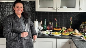 Une cuisine avec des meubles blancs, un plan de travail noir et divers plats et boissons disposés sur le comptoir.