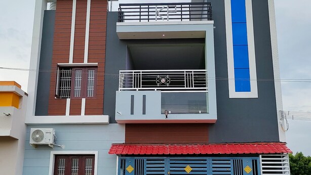 A modern two-story building with a balcony, a garage, and a red roof.