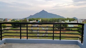 A balcony with a metal railing overlooking a residential area, a mountain in the background, and a clear sky.