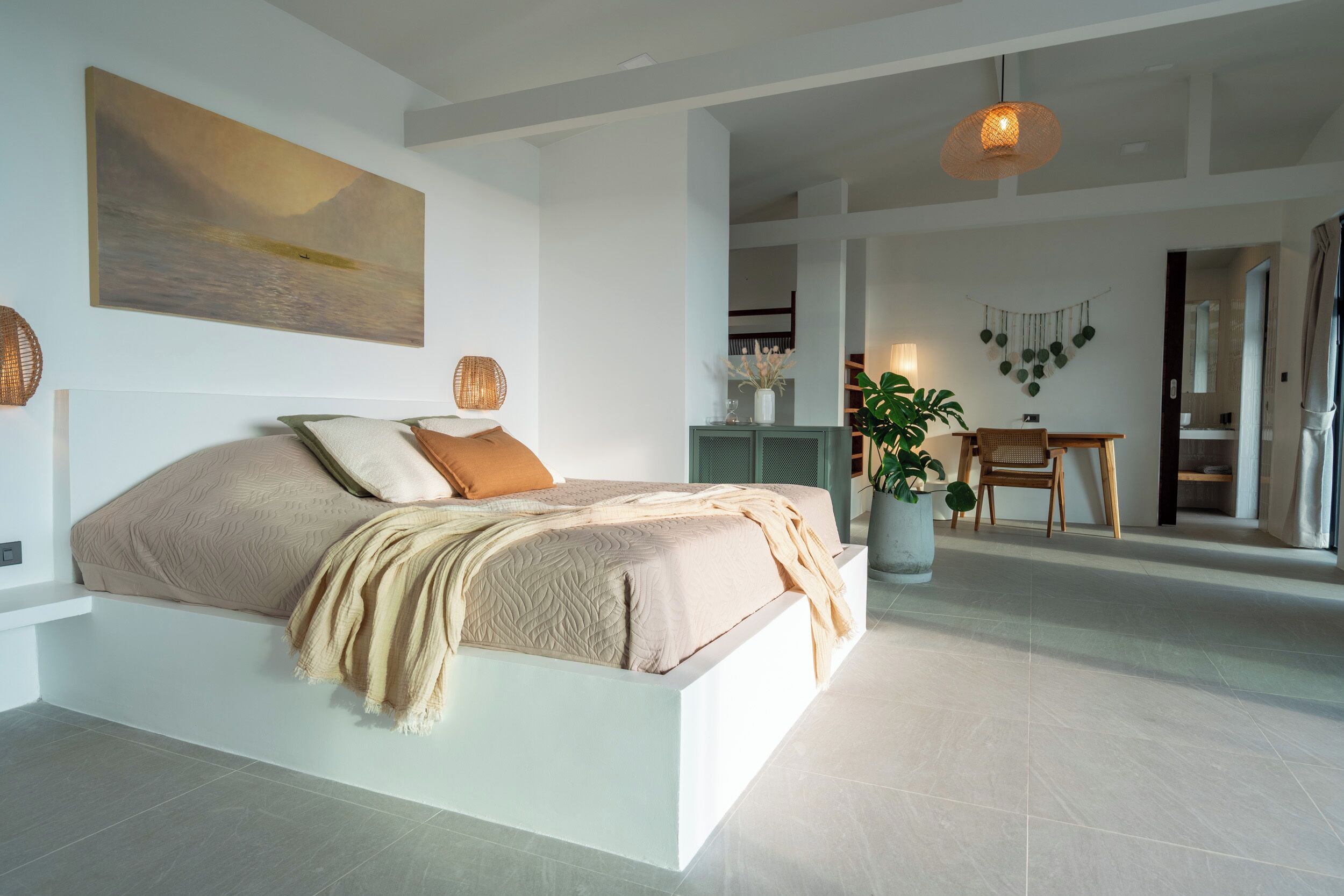 A modern bedroom with a large bed, a view of the outdoors, and a dining area with a plant.