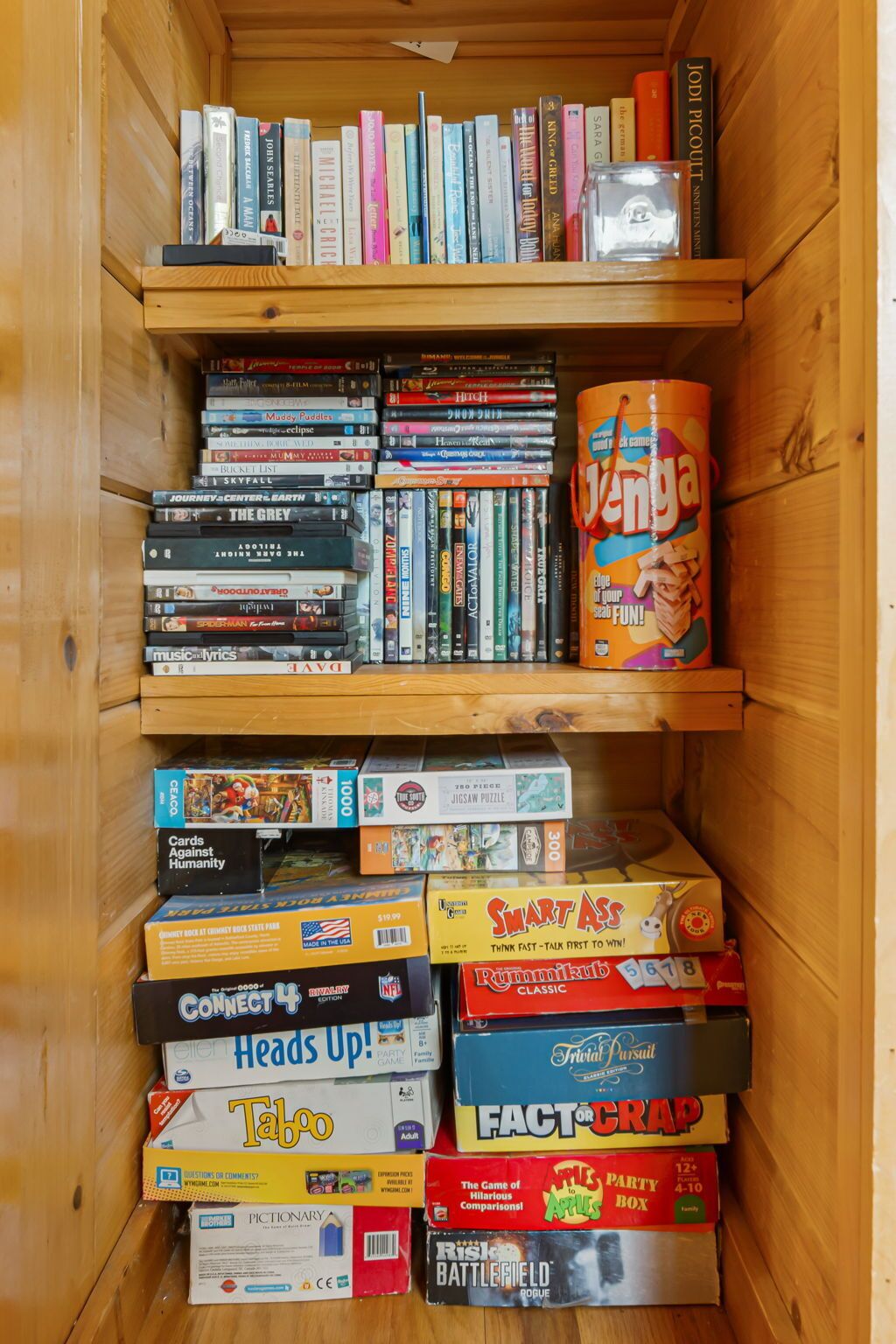 Uma estante repleta de livros, DVDs e jogos de tabuleiro.