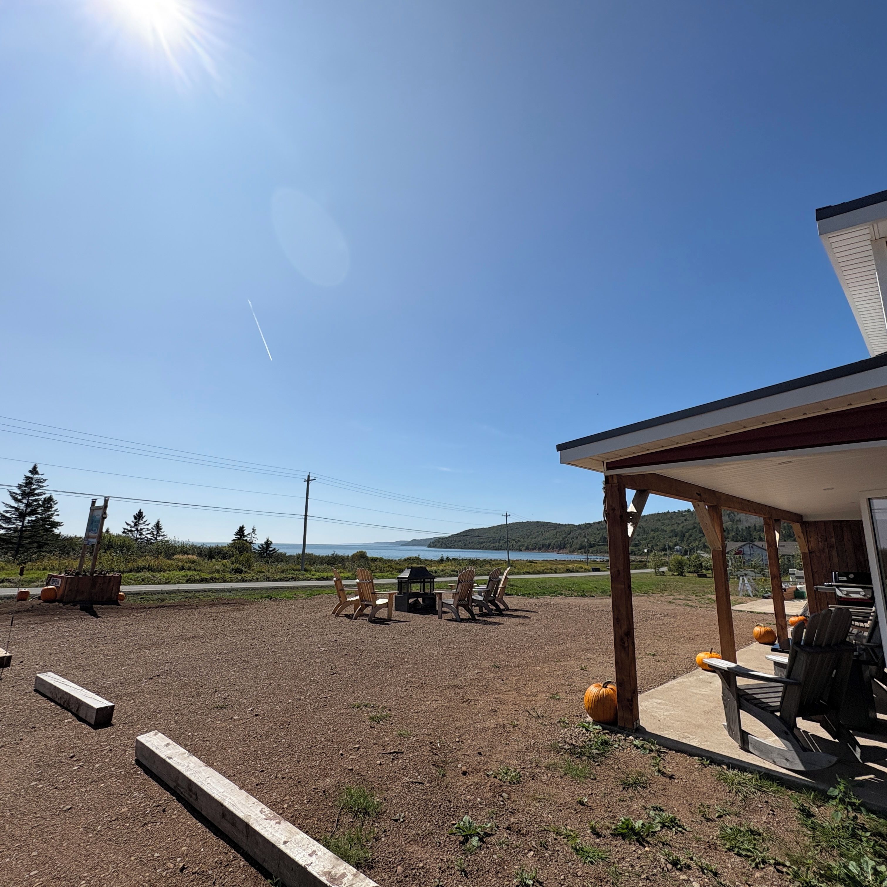 A covered outdoor seating area with a view of a lake and hills.