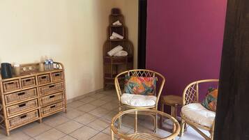 A room with wicker furniture, including a sofa and chairs, a small table with a coffee maker, and a wicker storage unit.