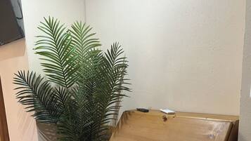 Un aparador de madera con una planta en maceta a su lado.