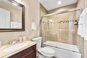 Un bagno con un ampio specchio, due lavabi, un water e una cabina doccia in vetro.