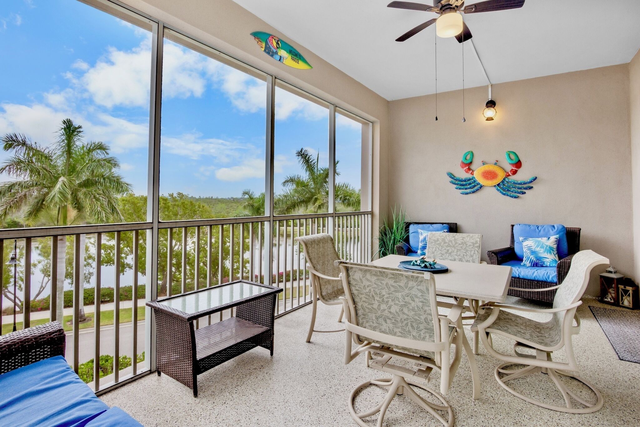 A balcony with a table and chairs, a ceiling fan, and a decorative crab wall art.