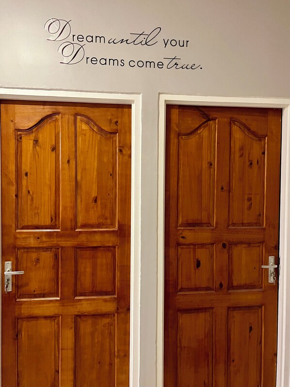 Two wooden doors with a decorative design and a motivational quote above them.
