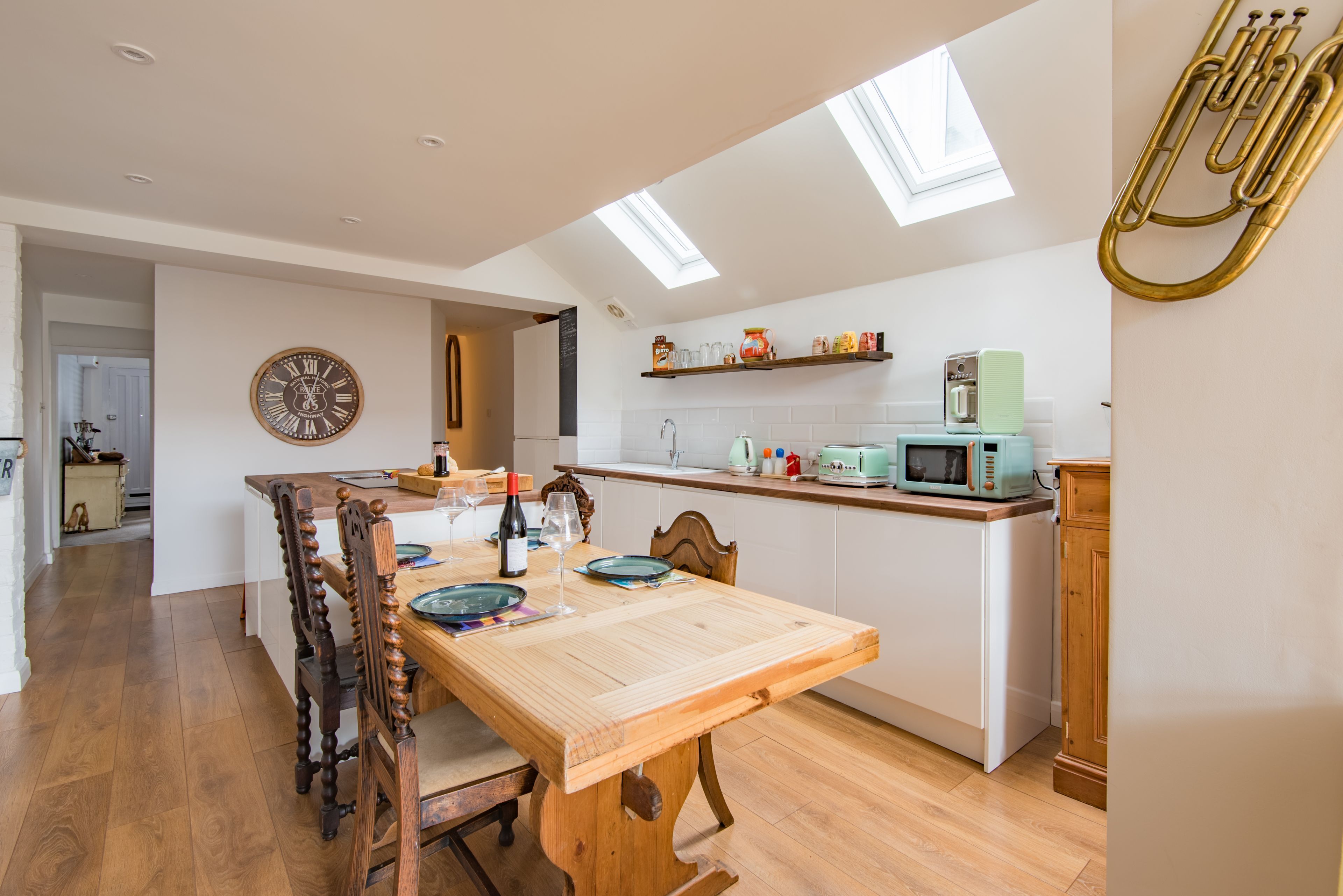 A modern kitchen with a wooden dining table, a clock, and a brass trumpet.