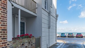 Ein Gebäude mit Balkon, Backsteinfassade und Straßenansicht mit parkenden Autos.