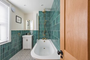 A bathroom with a bathtub, a sink, and a mirror. - Brook Cottage, Whitstable (Whitstable)