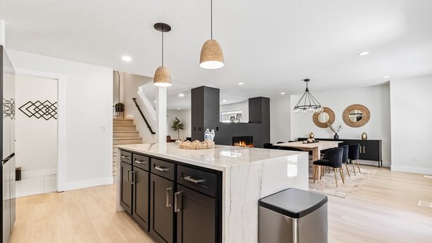 A modern kitchen with a marble island, black cabinets, and pendant lighting. - 5 Bedroom house in prime location by the village (Meridian)