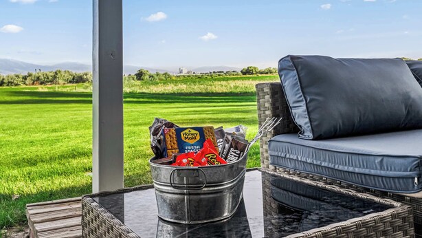 A wicker sofa with a cushion and a metal bucket filled with snacks on a table.