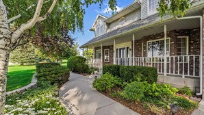 A two-story house with a covered porch, a well-maintained garden, and a clear pathway leading to the front door.