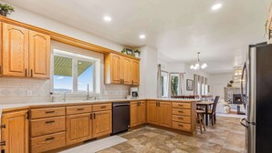 A modern kitchen with wooden cabinets, a dishwasher, and a large island with seating.