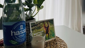 A bottle of water, a candle, a small potted plant, and a framed picture on a woven placemat. - Beautiful, sun-drenched vacation apartment on the Dünsberg - surrounded by greenery (Biebertal)