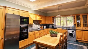 A modern kitchen with a skylight, stainless steel appliances, wooden cabinets, and a dining area.