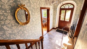 A grand staircase with a wooden handrail, a large ornate mirror, and a chandelier.