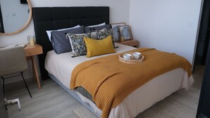 Une chambre à coucher bien rangée, avec un lit, des tables de chevet, une chaise et un miroir.
