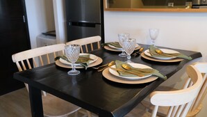 Une table à manger dressée avec des assiettes, des couverts et des verres, entourée de chaises.