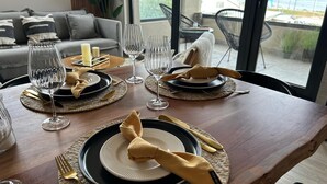 A dining table set with plates, cutlery, and wine glasses, with a view of the outdoors through large windows. - Apartment in Puerto Natales, cozy and with all the comforts you need. (Puerto Natales)