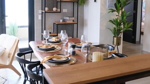 A modern dining area with a wooden table set for four, surrounded by black chairs. A unique black chandelier with multiple bulbs hangs above. - Apartment in Puerto Natales, cozy and with all the comforts you need. (Puerto Natales)