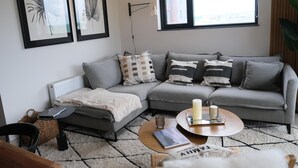 A modern living room with a grey sectional sofa, a round coffee table, and framed artwork on the wall. - Apartment in Puerto Natales, cozy and with all the comforts you need. (Puerto Natales)