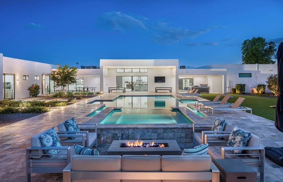A modern outdoor pool area with lounge chairs and a fire feature.