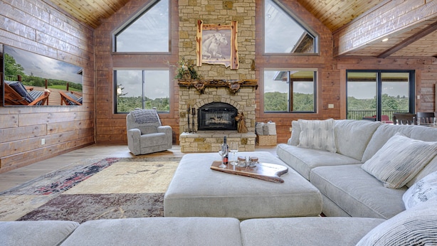 Un salón espacioso con chimenea de piedra, ventanas amplias y una zona de estar acogedora.