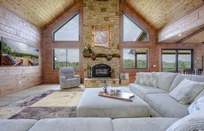 Un salón espacioso con chimenea de piedra, ventanas amplias y una zona de estar acogedora.