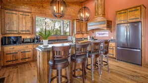 Una cocina amplia con armarios de madera, un refrigerador de acero inoxidable y una isla grande con taburetes de bar.