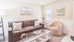 A living room with a brown sofa, a glass coffee table, and a beige armchair.