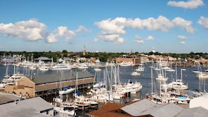 A marina with numerous boats docked, a prominent building with a flat roof, and a distant church spire.