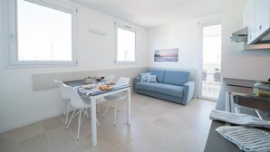 Una cocina moderna con comedor, un sofá azul y un ventanal grande.