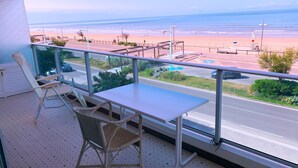 Un balcon donnant sur une plage, avec une table et deux chaises.