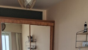 Une chambre à coucher avec un lit, une table de chevet, un miroir et une horloge au mur.