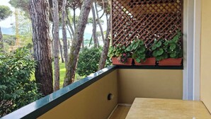 A balcony with a yellow tiled floor, a wooden table, and potted plants. - Bilo in residence+beach from 01/06/25 to 30/09/25 (Capanne-Prato-Cinquale)