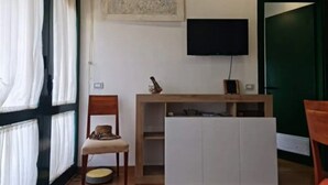 A room with a bed, a desk, a chair, a television, and a window with curtains. - Bilo in residence+beach from 01/06/25 to 30/09/25 (Capanne-Prato-Cinquale)