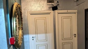 A hallway with two white doors, a decorative gold-framed mirror, and patterned floor tiles. - Old City Pansiyon (Istanbul)