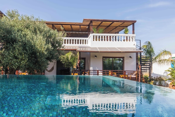 Un resort con piscina, area esterna coperta e vegetazione lussureggiante.