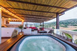 Un espace avec un bain à remous, une terrasse en bois, des sièges et une vue sur le paysage.