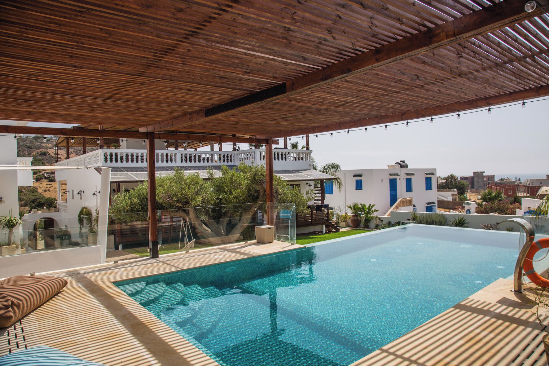 Une piscine sur le toit, dotée d’une terrasse en bois, d’un espace salon couvert et offrant une vue sur le paysage urbain.