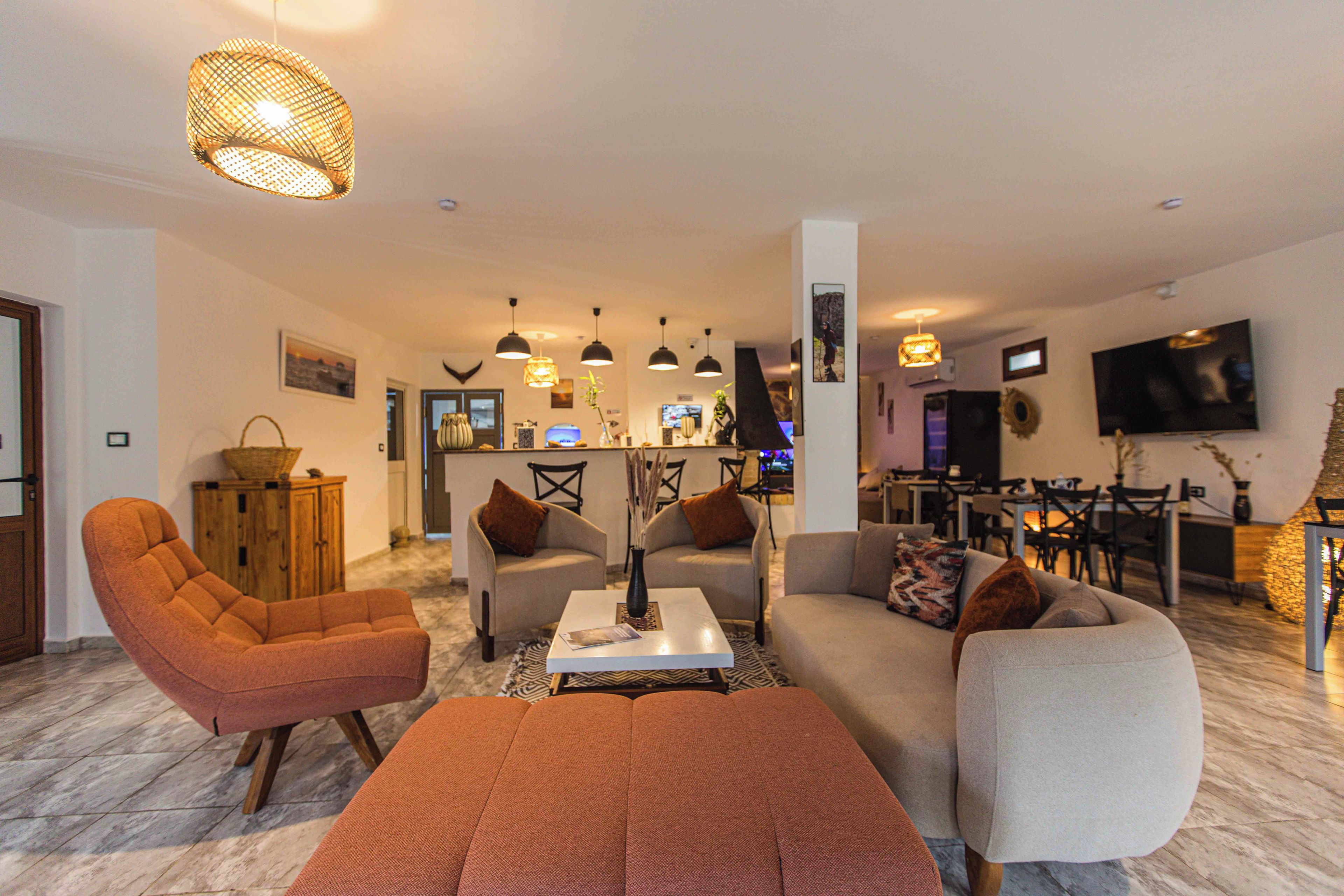 Ein Wohnzimmer mit einer Couch, Sesseln, einem Couchtisch und einem Fernseher.