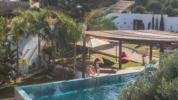 Una piscina rectangular con borde de azulejos, rodeada de césped y una terraza de madera.